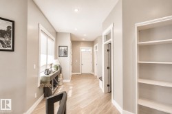 Bright interior hallway featuring light wood-finish flooring, recessed lighting, white baseboards, and built-in shelving - 