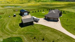 Sprawling property featuring a single-story residence with a three-car attached garage, a detached storage building, and a separate large workshop with an overhead door - 