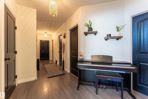 Hallway featuring wood-finish flooring and multiple dark paneled doors with black hardware - 4804 64 Avenue, Cold Lake, AB 
