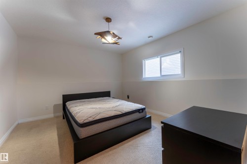 Room featuring carpeted flooring, a white-framed window with blinds, and a contemporary ceiling light fixture - 4804 64 Avenue, Cold Lake, AB 