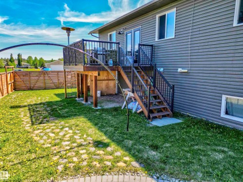 Raised wood deck with dark railing and steps, offering direct access to the outdoor area - 4804 64 Avenue, Cold Lake, AB 