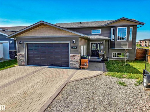 Modern split-level exterior featuring dark gray siding, a prominent two-car garage, and a paver driveway - 4804 64 Avenue, Cold Lake, AB 