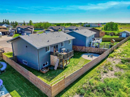 Expansive backyard featuring a manicured lawn, wood fencing, and a multi-level deck - 4804 64 Avenue, Cold Lake, AB 