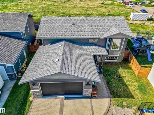 Two-story residence featuring a gray exterior with stone accents, a multi-gabled roofline, an attached garage, and a paver driveway - 4804 64 Avenue, Cold Lake, AB 