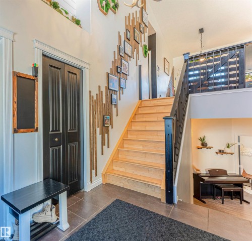 Entryway with light wood-finish stairs, dark wood-finish railing, and dark tile flooring - 4804 64 Avenue, Cold Lake, AB 