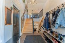 Two-story entryway featuring a hardwood staircase with black metal railings, a dual-door closet, and tile flooring - 4804 64 Avenue, Cold Lake, AB 
