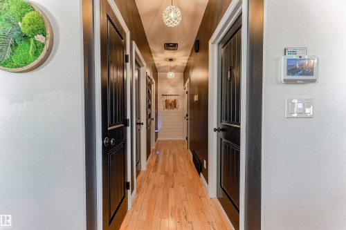 Hardwood flooring extends throughout this hallway, featuring dark paneled doors with white trim - 4804 64 Avenue, Cold Lake, AB 