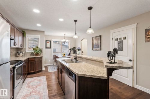 Kitchen with wood-finish flooring, recessed lighting, and a peninsula featuring a double basin sink with a high-arch faucet - 1542 33A St Nw, Edmonton, AB 