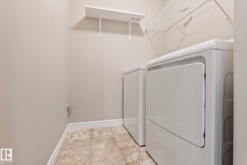 Dedicated laundry area featuring textured tile flooring and light-toned walls - 1542 33A St Nw, Edmonton, AB 