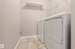 Dedicated laundry area featuring textured tile flooring and light-toned walls - 