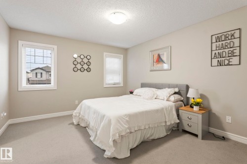 Room featuring two windows with white blinds, neutral carpeting, and light-colored wall paint - 1542 33A St Nw, Edmonton, AB 
