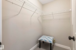 Closet interior featuring neutral wall paint, white wire shelving, white trim, and gray carpet flooring - 