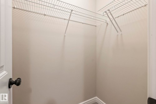 Walk-in closet featuring wire shelving, neutral wall paint, white trim, and wood-finish flooring - 1542 33A St Nw, Edmonton, AB 