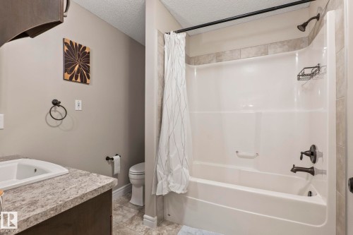 Bathroom featuring a white shower-tub combination with a dark-toned showerhead and faucet, set against tile surround - 1542 33A St Nw, Edmonton, AB 