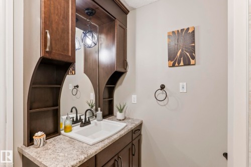 Bathroom vanity featuring a rectangular sink, dark wood-finish cabinetry, and a textured countertop - 1542 33A St Nw, Edmonton, AB 
