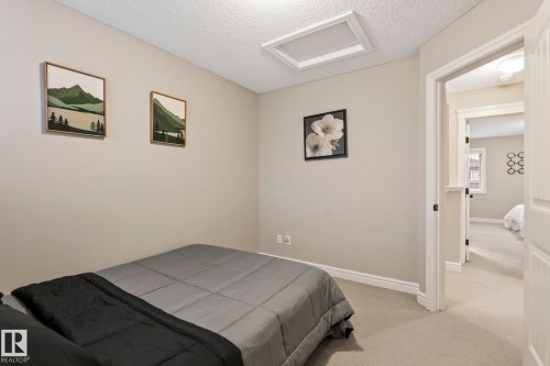 Carpeted room with a textured ceiling and a white trim baseboard - 1542 33A St Nw, Edmonton, AB 