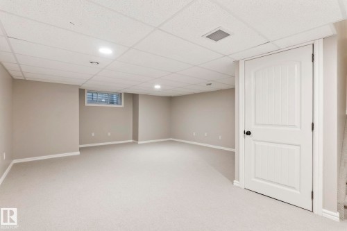 Spacious finished room featuring light gray carpeting, neutral wall paint, white trim, recessed lighting, and a drop ceiling - 1542 33A St Nw, Edmonton, AB 