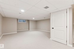 Spacious finished room featuring light gray carpeting, neutral wall paint, white trim, recessed lighting, and a drop ceiling - 