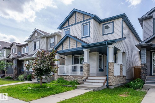 Two-story residence featuring light-colored siding, contrasting blue trim, and stone accents - 1542 33A St Nw, Edmonton, AB 