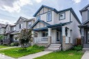 Two-story residence featuring light-colored siding, contrasting blue trim, and stone accents - 1542 33A St Nw, Edmonton, AB 