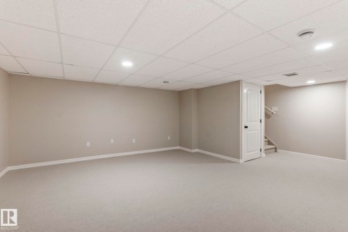 Spacious finished basement featuring light gray carpeting, neutral wall tones, white trim, and a drop ceiling with recessed lighting - 1542 33A St Nw, Edmonton, AB 