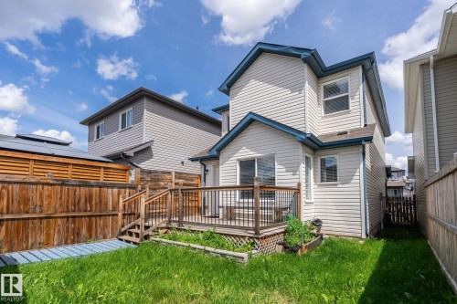 Rear exterior featuring a ground-level deck, wood fencing, and a grassy yard space - 1542 33A St Nw, Edmonton, AB 