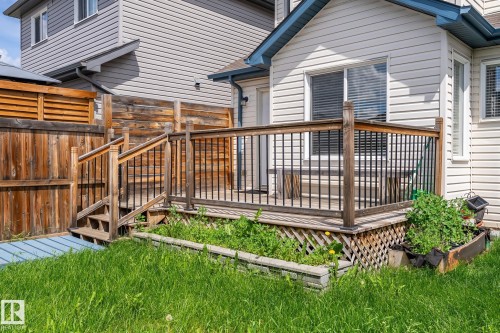Rear deck with wood railing and black balusters, featuring a lattice skirting - 1542 33A St Nw, Edmonton, AB 
