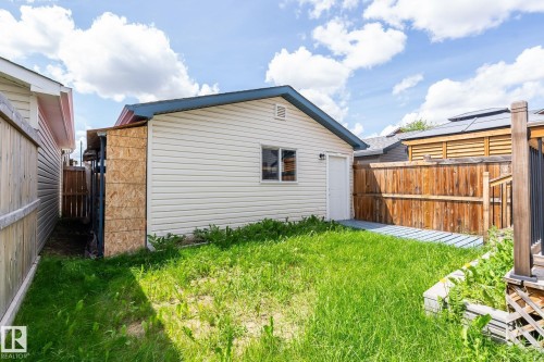 Freestanding outbuilding with horizontal siding and a single window, featuring a metal roof and an attached lean-to structure - 1542 33A St Nw, Edmonton, AB 