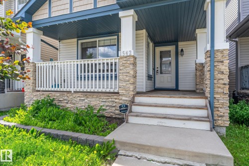 Front porch entry with stone accents, white railing, and blue ceiling detail - 1542 33A St Nw, Edmonton, AB 