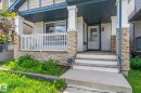 Front porch entry with stone accents, white railing, and blue ceiling detail - 1542 33A St Nw, Edmonton, AB 
