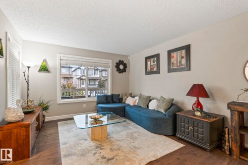 Spacious living area featuring neutral wall tones, durable wood-finish flooring, and a large window with white blinds - 1542 33A St Nw, Edmonton, AB 