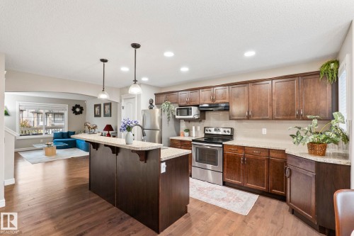 Modern kitchen featuring stainless steel appliances, wood-finish cabinetry, and light-toned countertops - 1542 33A St Nw, Edmonton, AB 