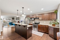 Modern kitchen featuring stainless steel appliances, wood-finish cabinetry, and light-toned countertops - 