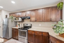 Kitchen featuring extensive wood cabinetry with modern hardware, speckled countertops, and stainless steel appliances - 