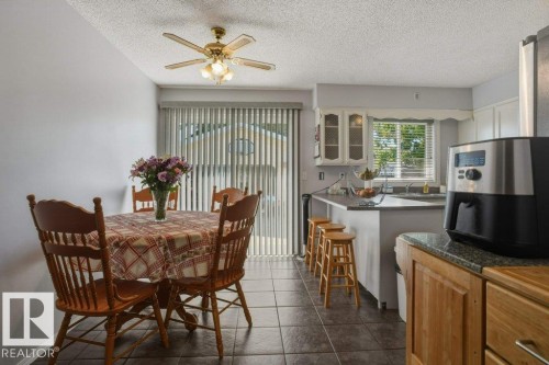 Open-concept dining area featuring dark tile flooring and a ceiling fan with integrated lighting - 8901 94 Avenue, Fort Saskatchewan, AB 