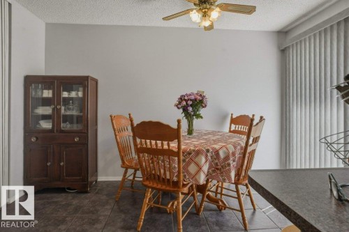 Dining area featuring dark-toned tile flooring, light gray walls, and a ceiling fan with integrated lighting - 8901 94 Avenue, Fort Saskatchewan, AB 