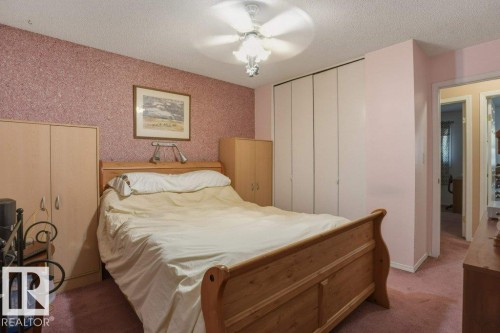 Bedroom featuring textured wall covering, a ceiling fan with integrated lighting, and light-colored carpeting - 8901 94 Avenue, Fort Saskatchewan, AB 