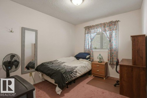 Bedroom featuring a window with blinds, a ceiling-mounted light fixture, and textured wall-to-wall carpeting - 8901 94 Avenue, Fort Saskatchewan, AB 