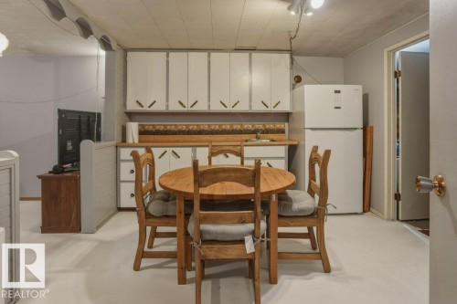 Kitchenette area featuring white cabinetry, light wood-finish countertops, and a white refrigerator - 8901 94 Avenue, Fort Saskatchewan, AB 