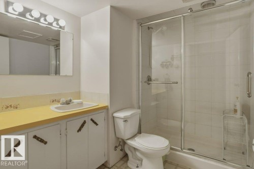 Bathroom featuring a glass-enclosed shower, built-in vanity with integrated sink, overhead lighting fixture, wall-mounted mirror, and tile flooring - 8901 94 Avenue, Fort Saskatchewan, AB 