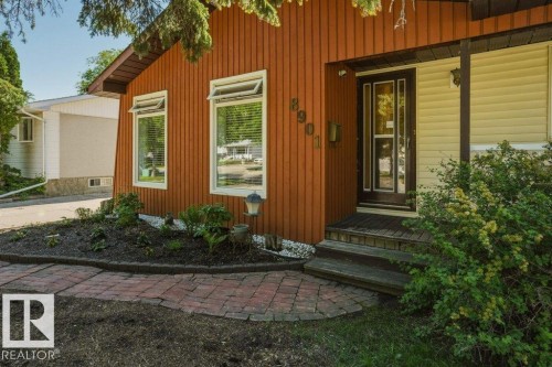 Vertical wood siding exterior with white trim windows and a dark wood entry door - 8901 94 Avenue, Fort Saskatchewan, AB 