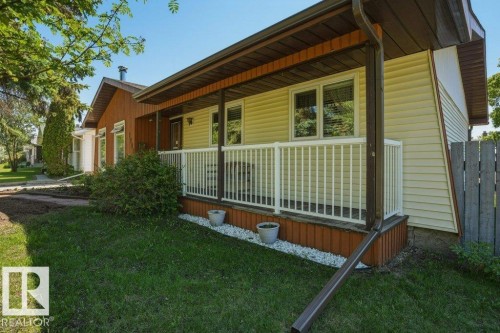 Covered front porch featuring white railing, light-colored siding, and a partial privacy fence - 8901 94 Avenue, Fort Saskatchewan, AB 