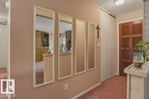 Entryway featuring a paneled wood door, flush-mount ceiling light, and full-length mirrors - 8901 94 Avenue, Fort Saskatchewan, AB 