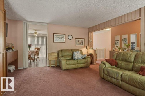 Spacious living area featuring plush carpeting and a wide entryway to an additional room with tiled flooring - 8901 94 Avenue, Fort Saskatchewan, AB 