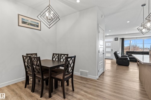Dining area featuring a contemporary geometric chandelier and wood-finish flooring - 8046 Kiriak Link, Edmonton, AB - Indoor Photo Showing Dining Room
