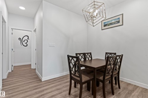 Dining area featuring a geometric chandelier and wood-finish flooring - 8046 Kiriak Link, Edmonton, AB - Indoor Photo Showing Dining Room
