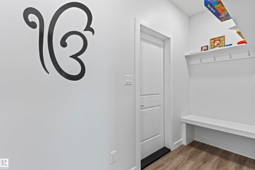 Entryway featuring wood-finish flooring, a white paneled door, and built-in white shelving with integrated hooks and a bench - 8046 Kiriak Link, Edmonton, AB - Indoor Photo Showing Other Room