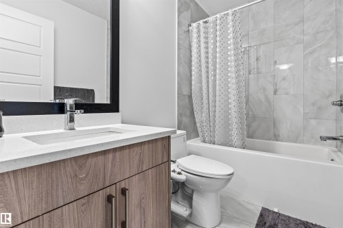 Bathroom featuring a wood-finish vanity with a light-toned countertop, an integrated sink, and a chrome faucet - 8046 Kiriak Link, Edmonton, AB - Indoor Photo Showing Bathroom