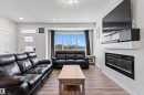 Living area featuring light wood-finish flooring, recessed lighting, and a wide window with dark drapery - 8046 Kiriak Link, Edmonton, AB  - Indoor Photo Showing Living Room With Fireplace 