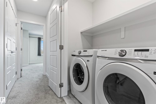 Dedicated laundry area featuring front-loading washer and dryer units, a full-width upper shelf, and light wood-finish flooring - 8046 Kiriak Link, Edmonton, AB - Indoor Photo Showing Laundry Room